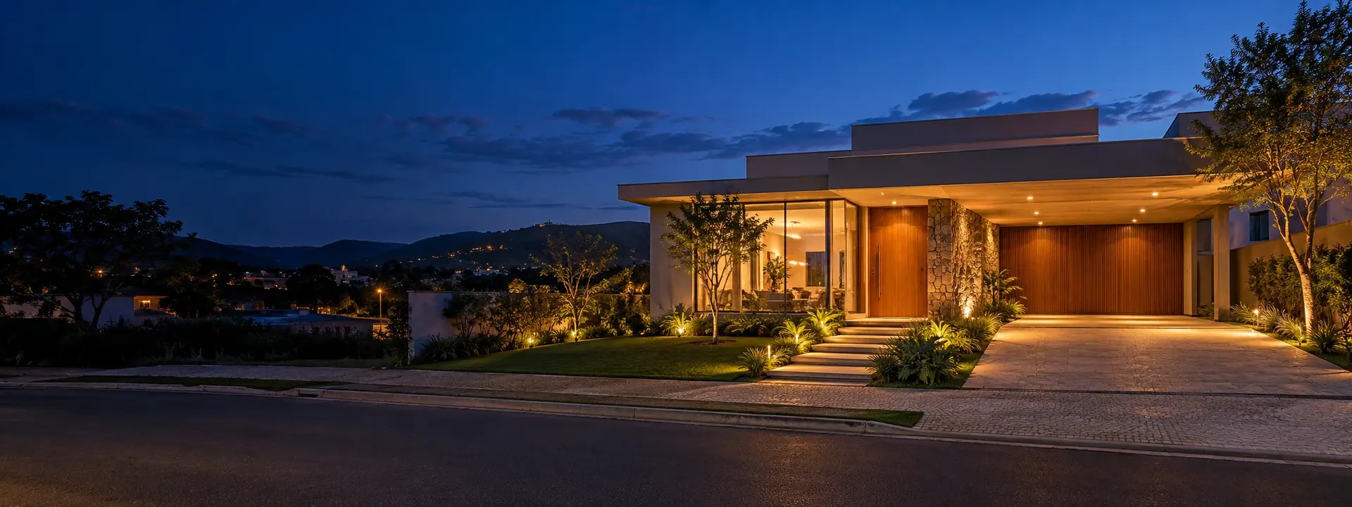 Casa contemporânea brasileira iluminada ao anoitecer em bairro do interior